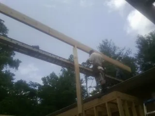 Carpenter setting a ridge beam over a new addition frame — Ice Dam Removal by Roofing Brothers in Pine Lake
