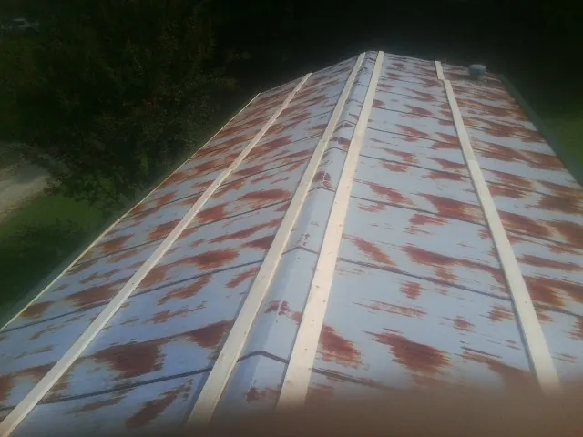 Rusted metal roof panels with new wood purlins before replacement — Storm Damage Roof Repair in Pine Lake by Roofing Brothers