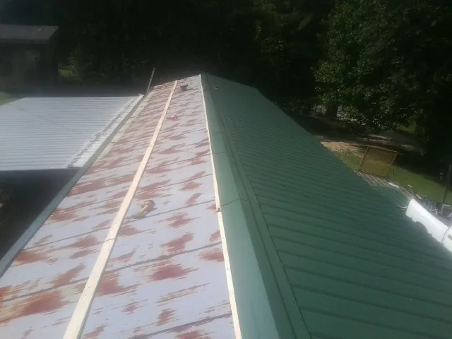 Old rusted panels beside newly installed green metal roofing — Wind Damage Roof Repair by Roofing Brothers in Pine Lake