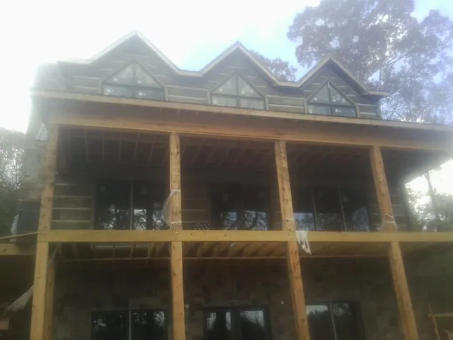 Dormers and porch framing on a large log home under construction — Roof Coating work by our crew in Pine Lake