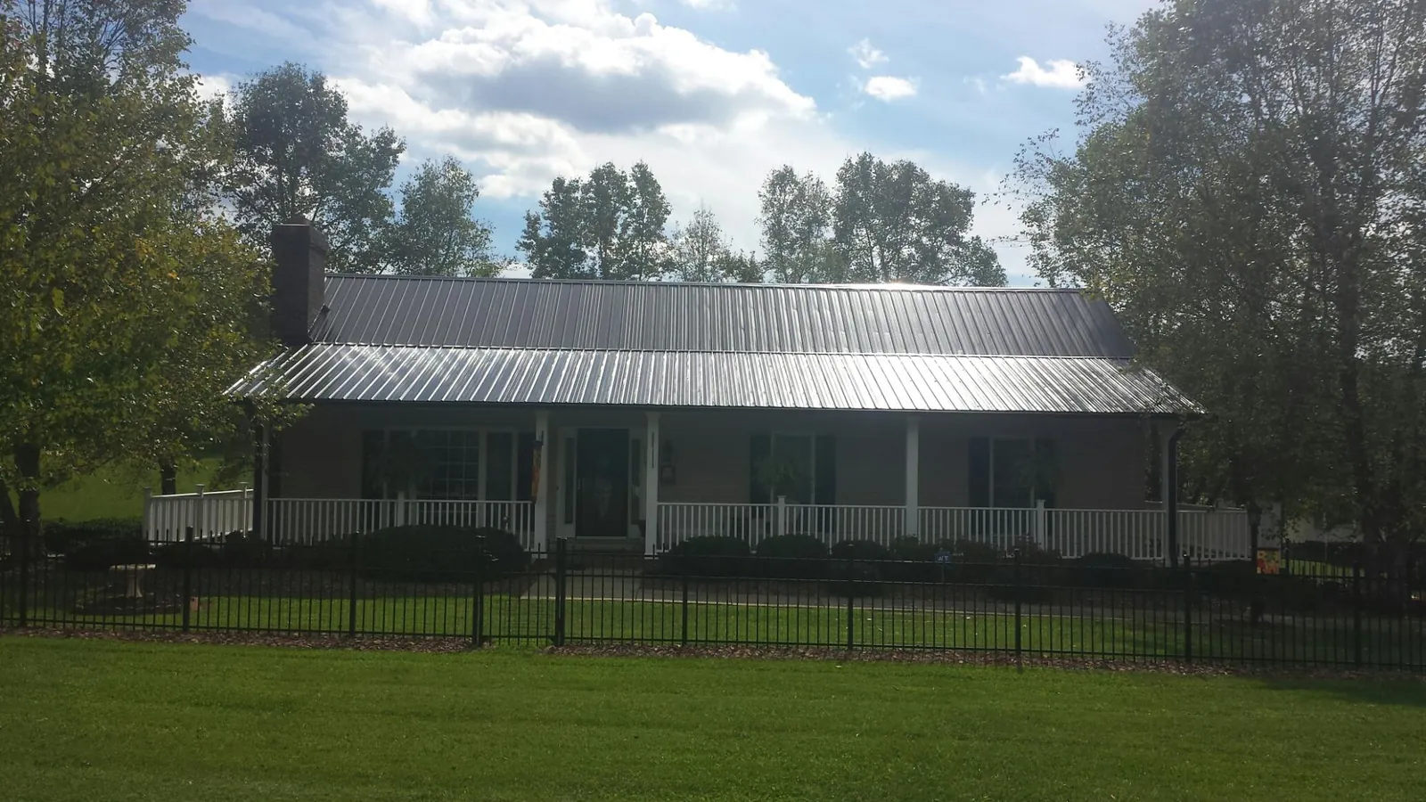 Gray metal roof on a brick ranch with a full width front porch — Gutter Guard Installation work by our crew in Pine Lake
