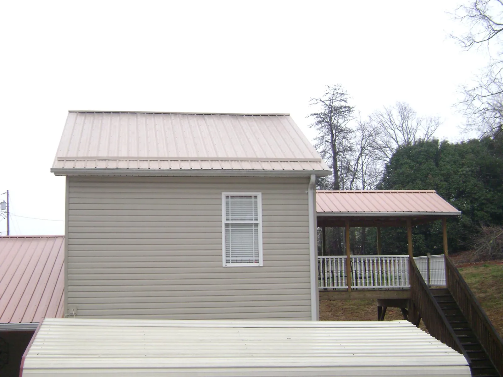Tan metal roofs on a two story addition and attached porch, from a Roof Replacement job in Pine Lake