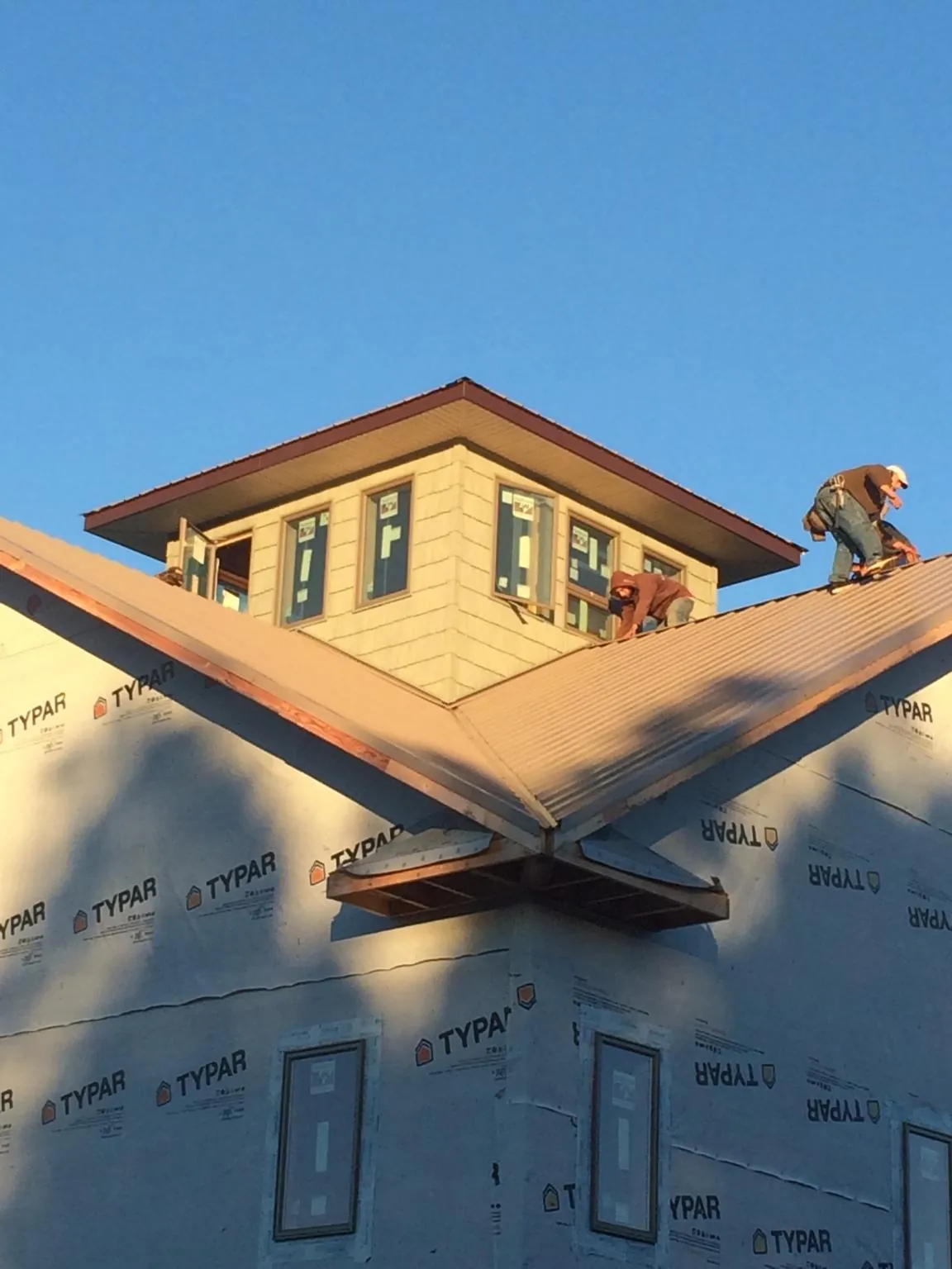 Roofers working around a rooftop cupola on a new metal roof at sunset — Roof Waterproofing in Pine Lake by Roofing Brothers